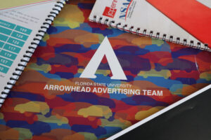 A collection of vintage Arrowhead Advertising NSAC plans books from the 1990s and 2000s, showcasing the program's long-standing history in the School of Communication.