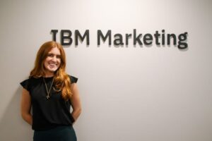 Kassidy Saba standing in front of IBM Marketing sign, looking excited. 